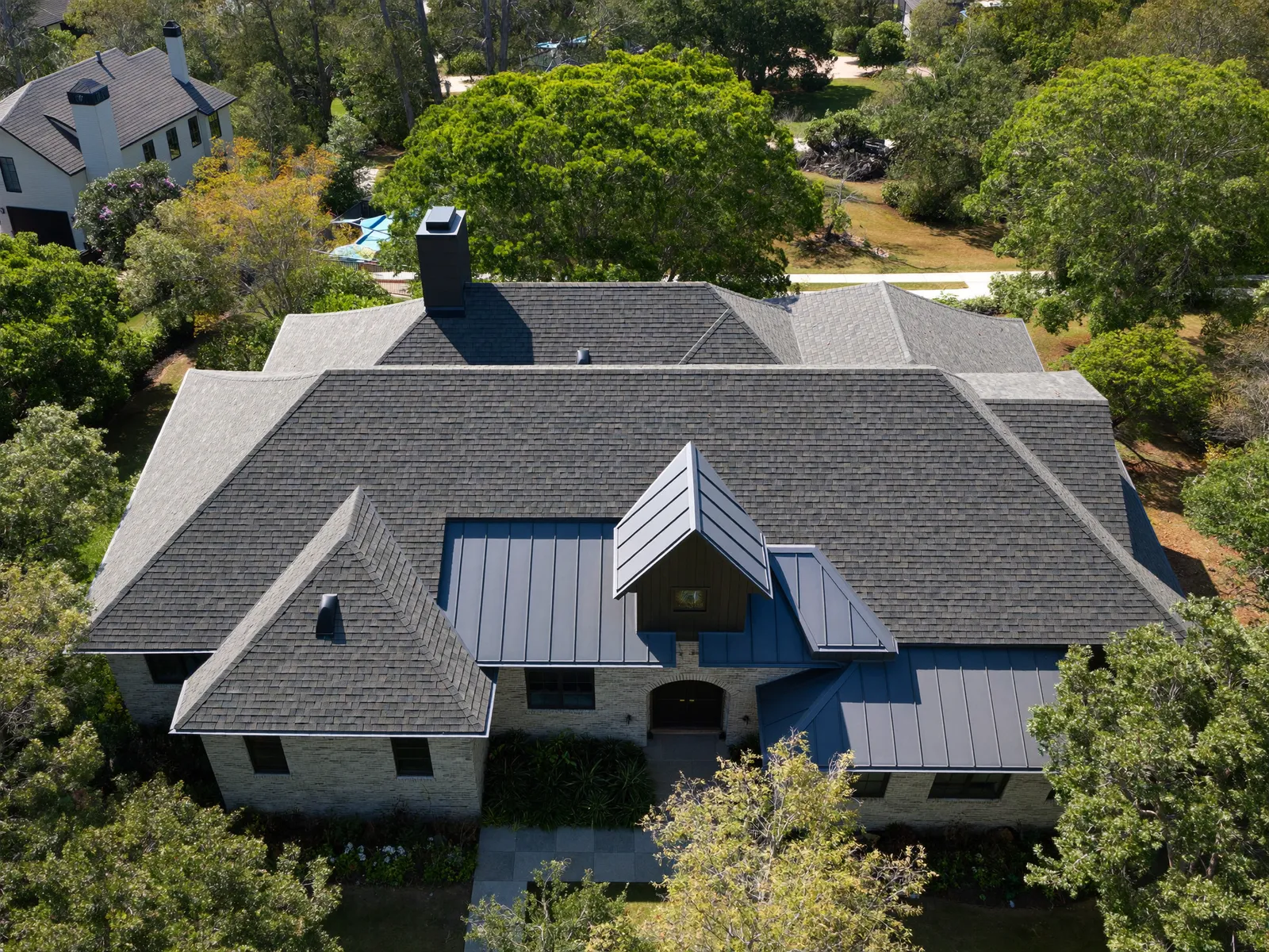 Aerial view of a steep shingle hip roof with metal accents