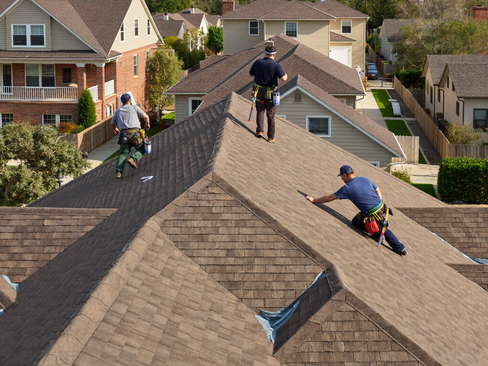 Three workers on a shingle roof seen from above