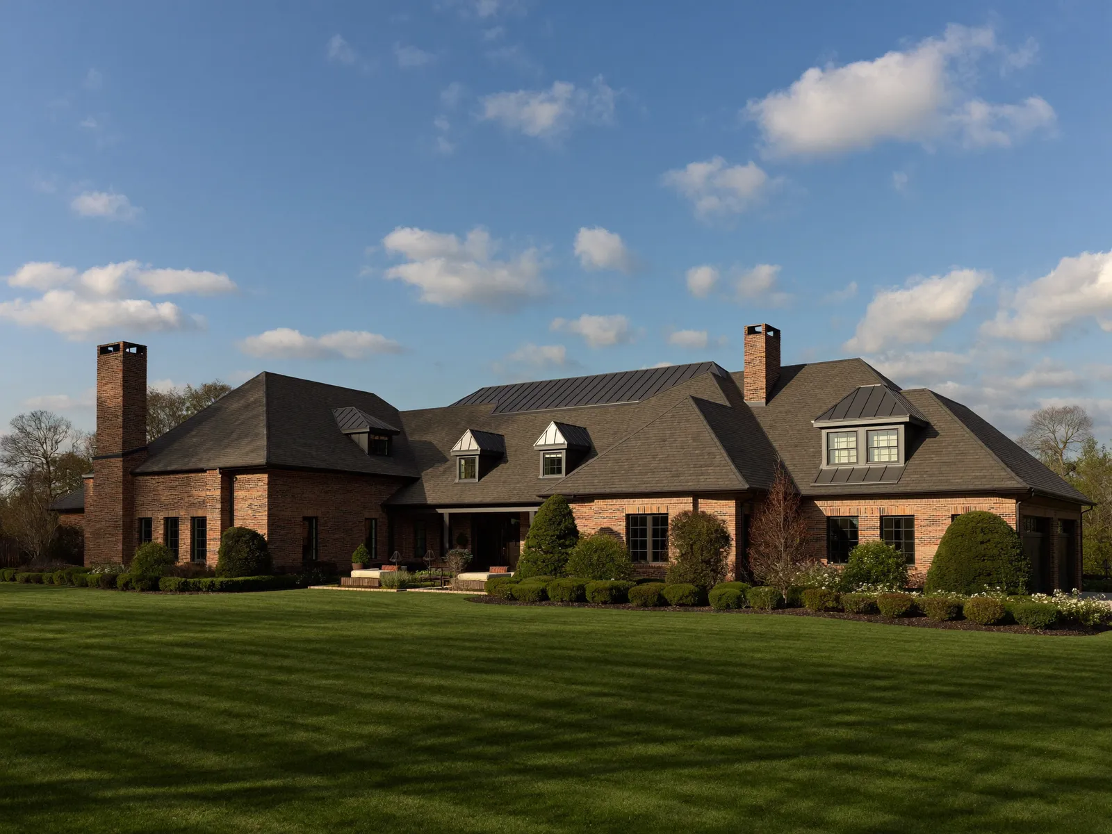 Custom brick estate home with a shingle and standing-seam metal roof